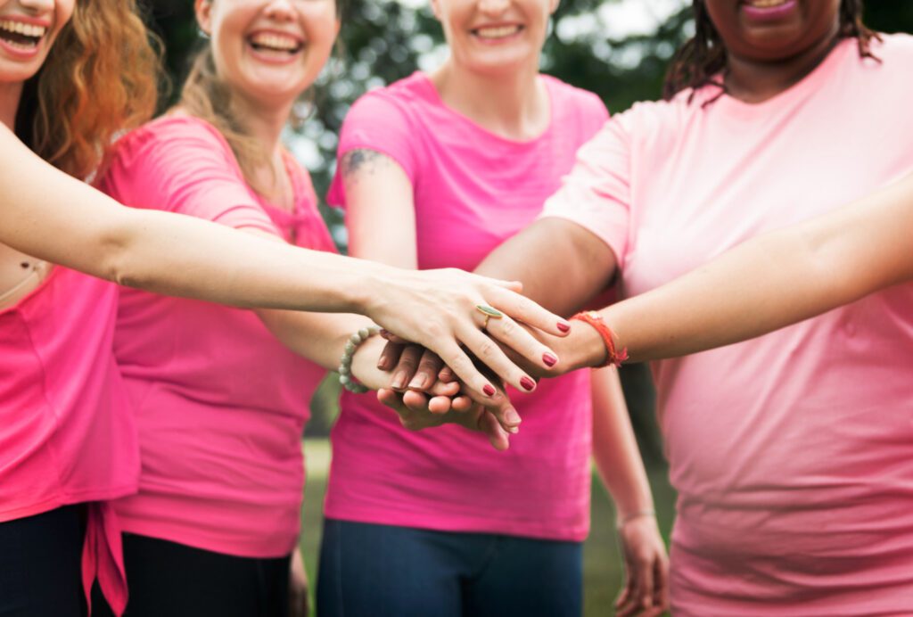 grupo-de-mulheres-com-maos-unidas-para-campanha-de-outuro-rosa