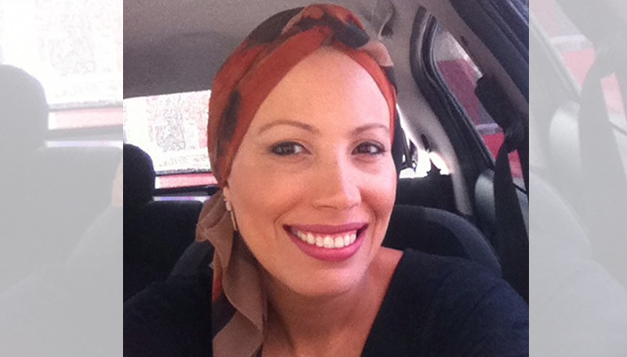 mulher com lenço na cabeça sorrindo durante quimioterapia