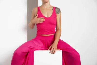 mulher-com-diagnostico-de-cancer-sentada-em-bloco-branco-com-roupas-cor-de-rosa