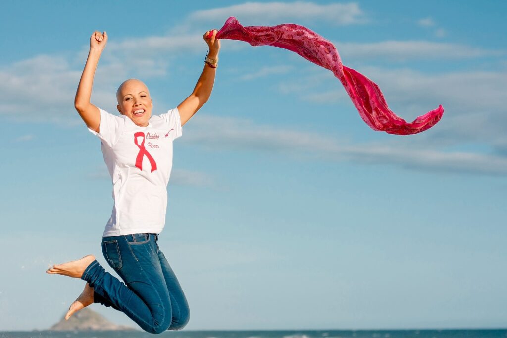 mulher pulando com lenço rosa em frente a fundo azul